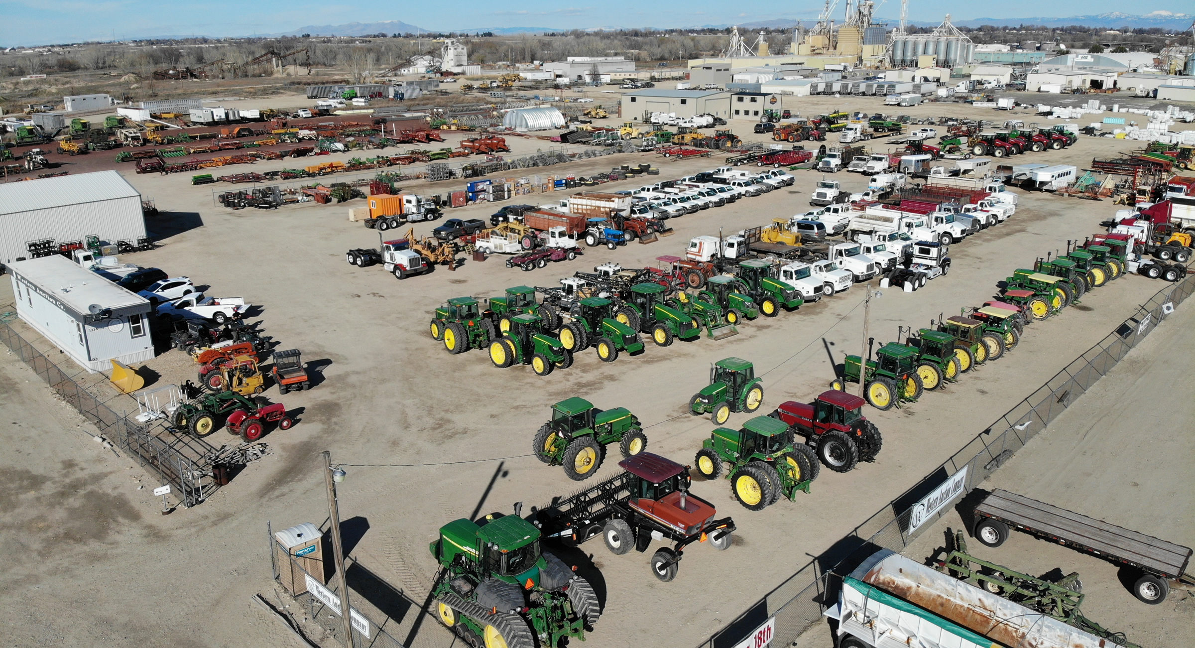 Open Consignment Auction. Aerial view of a lot filled with green tractors and heavy equipment.